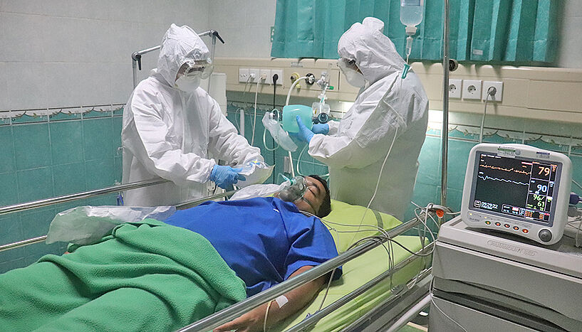Picture of a patient, lying in the hospital, next to him two doctors