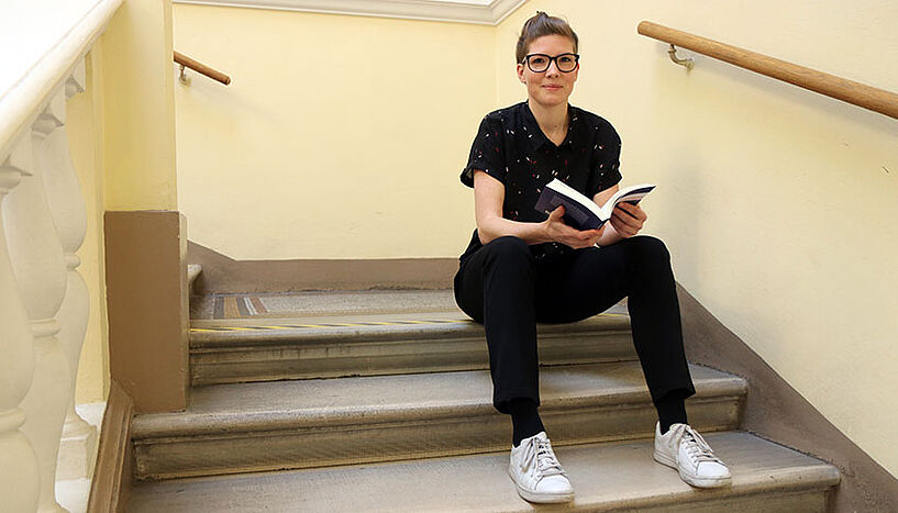 Carina Altreiter mit Buch auf einer Treppe sitzend