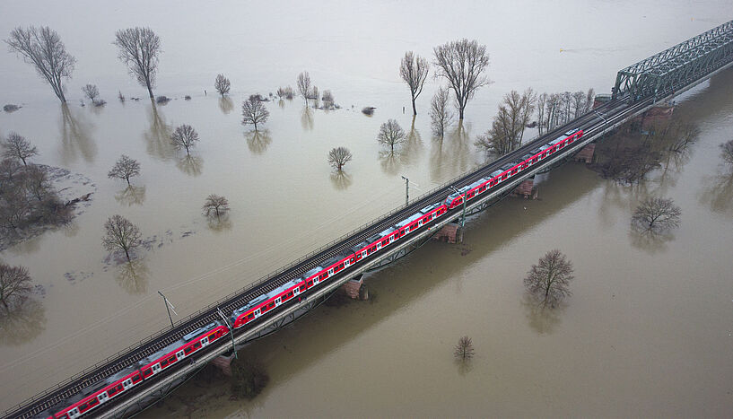 Ganze Landstriche im Main/Rhein-Gebiet, die überflutet sind. Nur einzelne Baumkronen ragen noch hervor. Den Fluten trotzt allerdings die Bantrasse - Dank der hohen Brücke fährt der Zug immer noch.