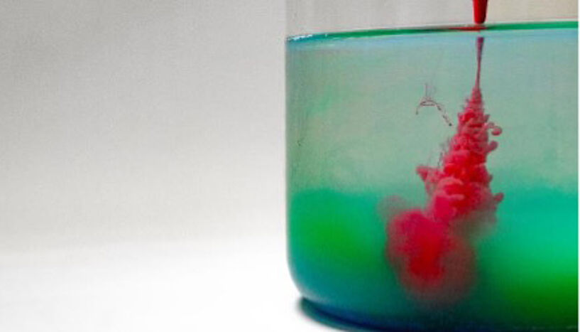 Abb. 1: Reagenzglas mit einer grünen Flüssigkeit, in das mit einer Pipette eine rote Flüssigkeit gegeben wird. 