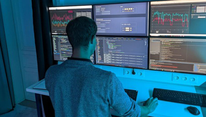 A man sitting in front of a multi-screen computer terminal