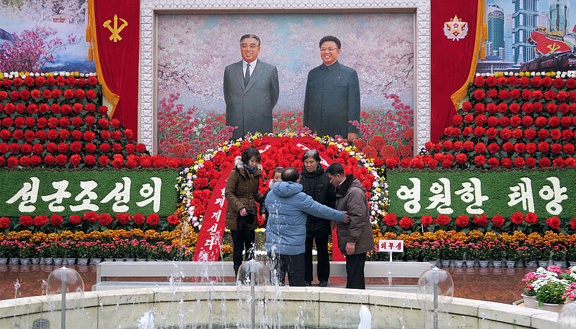 Eine Familie bereitet sich auf ein gemeinsames Foto vor dem Bildnis der politischen Führer vor.
