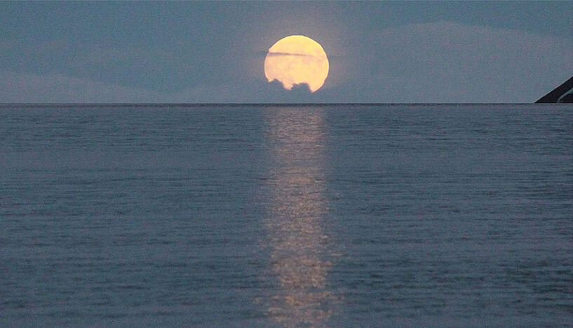 Der Mond geht über dem Meer unter
